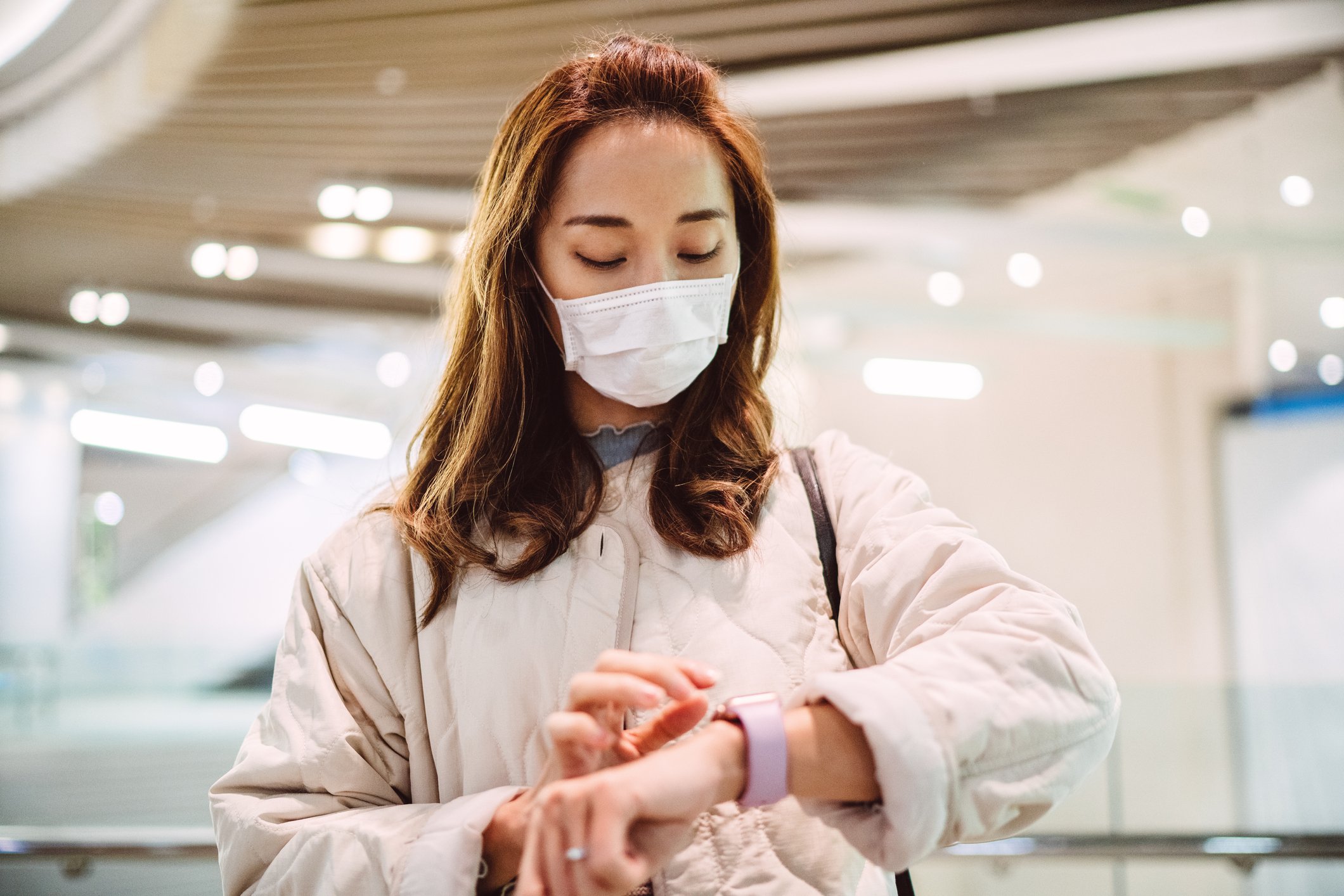 Woman in face mask using a smartwatch.