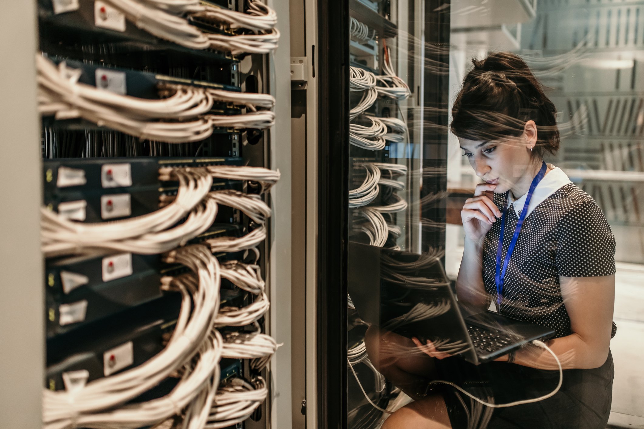 A woman working in a computer server room.