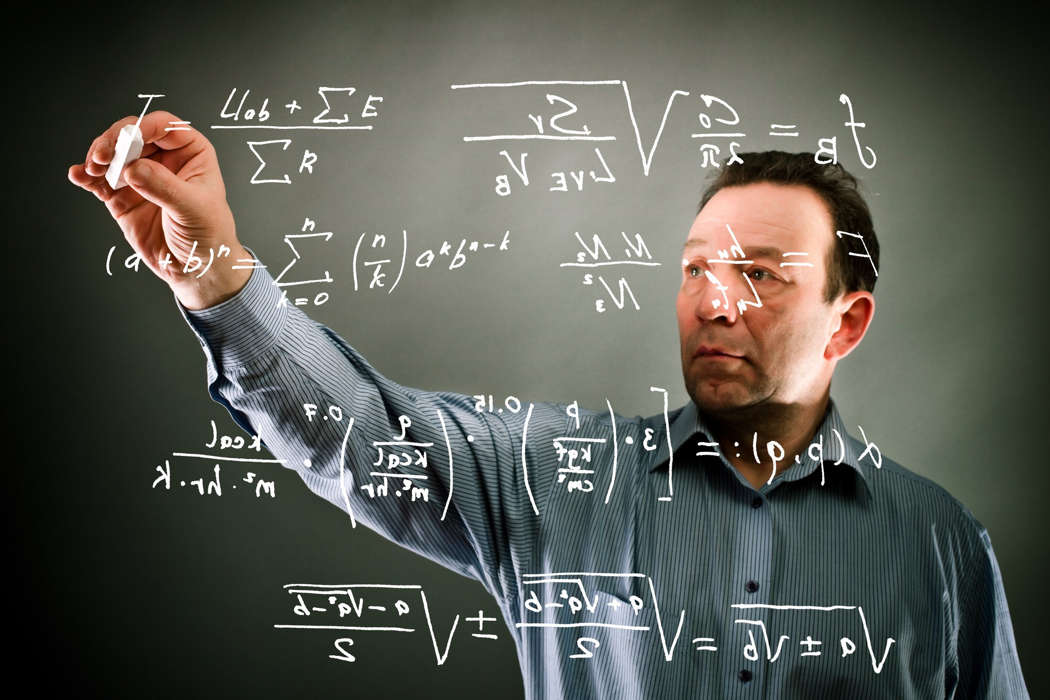 A man is writing out scientific equations on a plane of glass.