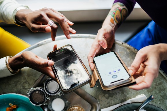 Two people share information on their smartphones.