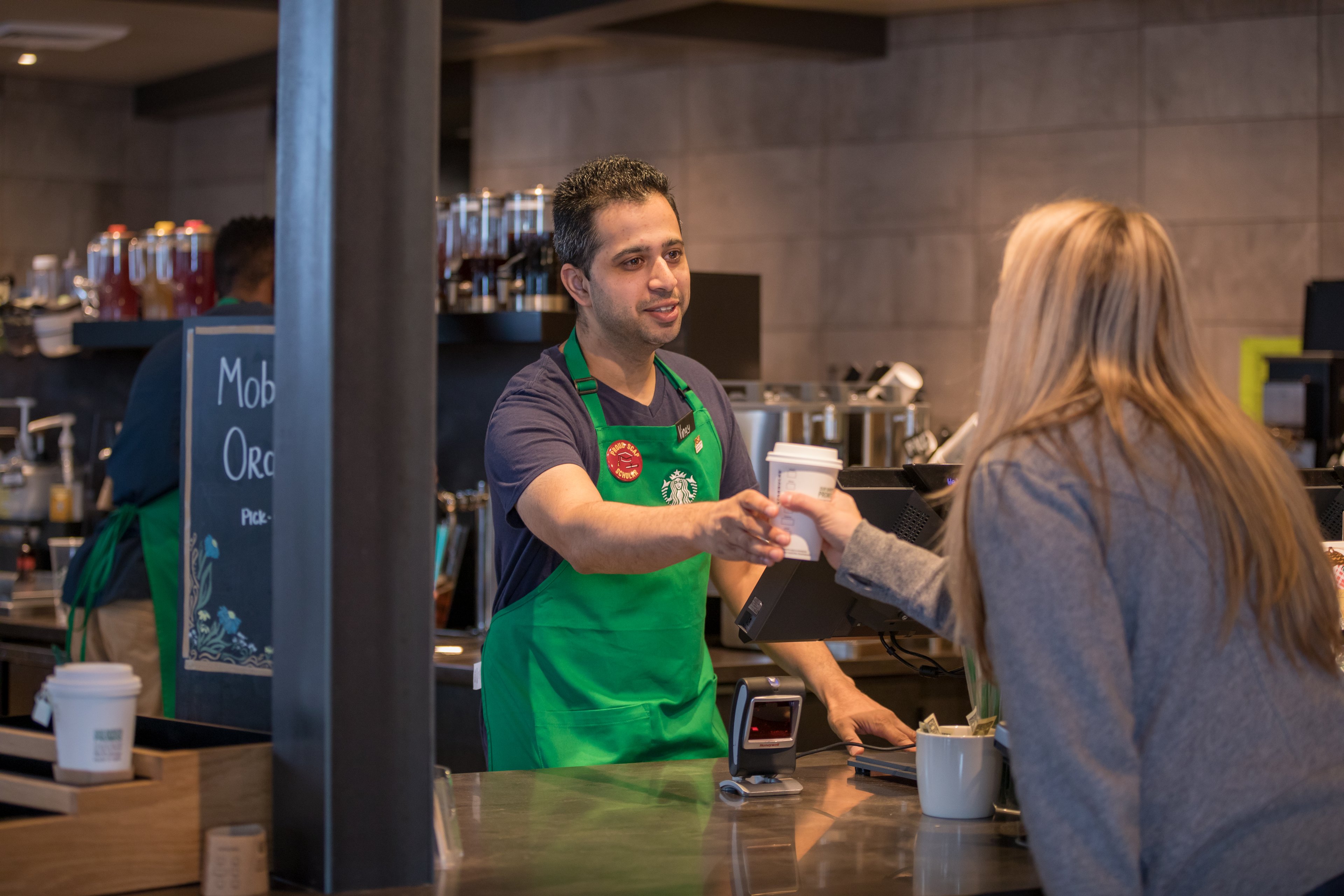 A Starbucks barista serving coffee to a customer.