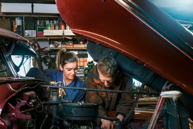 man and woman working on car
