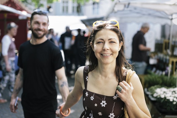 Woman smiling in outdoor market because she knows she's saving for retirement.