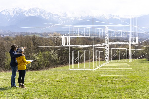 Two people look out over an empty lot in the mountains, imagining a home built to their specifications.