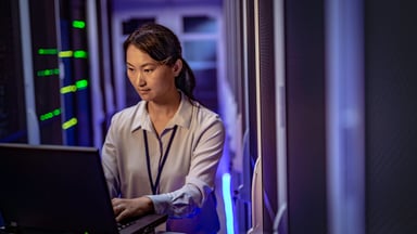 A woman on a computer in a server room