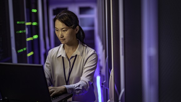 A woman on a computer in a server room