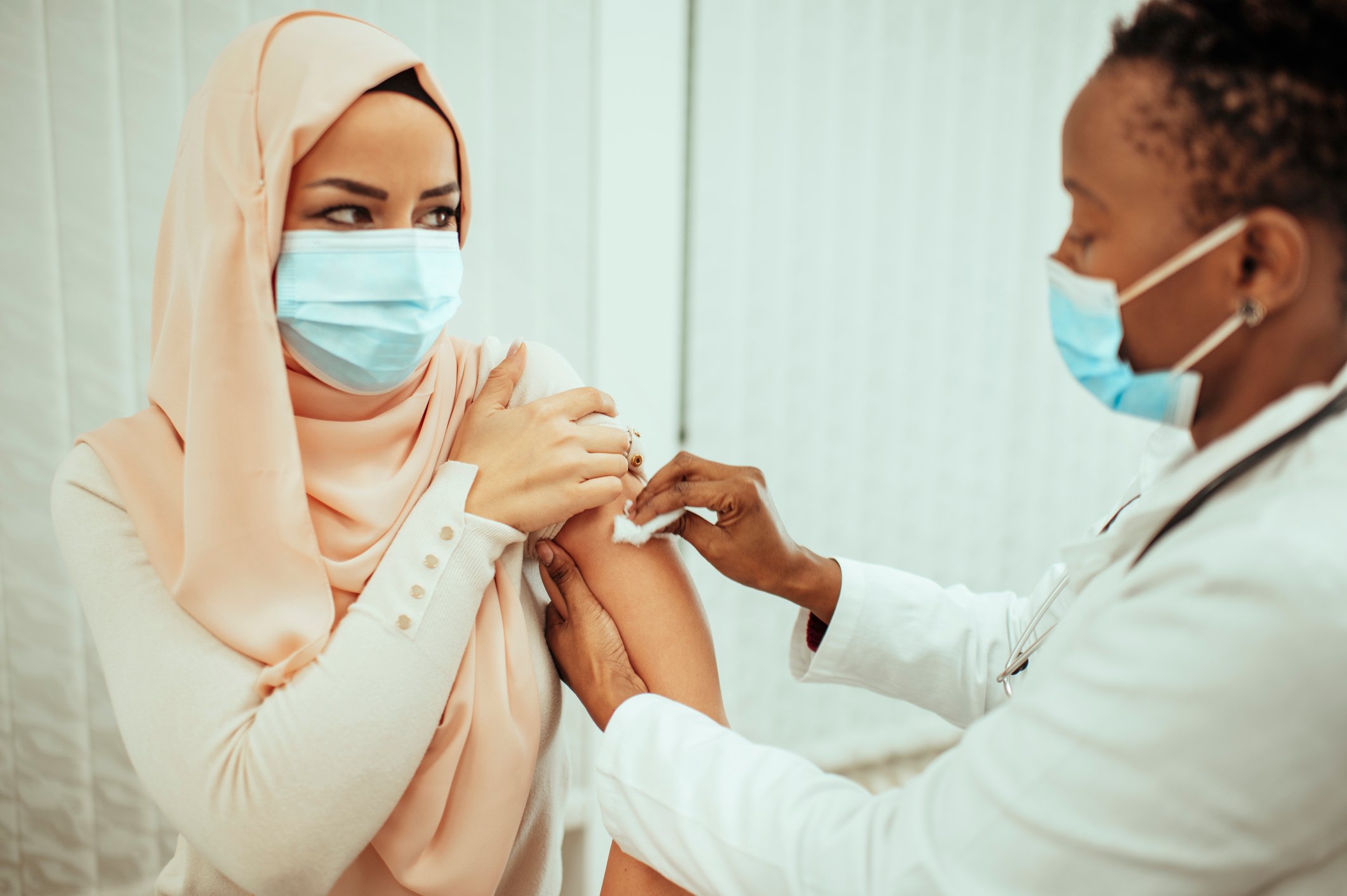 A nurse wiping down a person's arm in preparation for a shot.