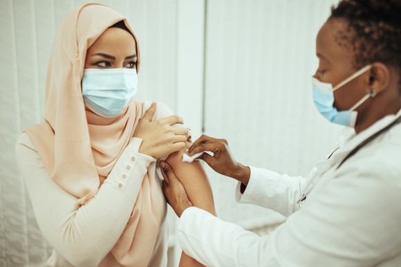 A nurse wiping down a person's arm in preparation for a shot.