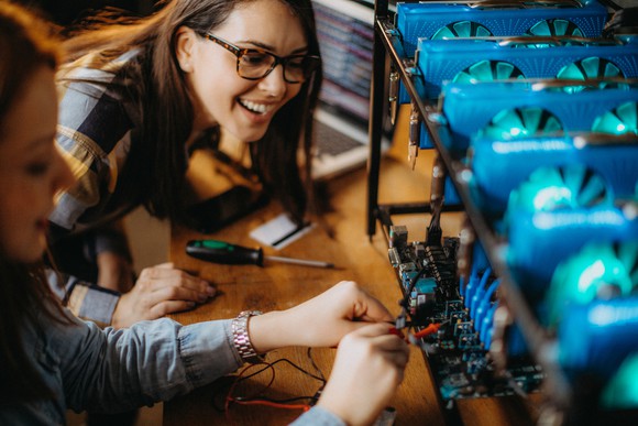 Two people working on a cryptocurrency mining rig. 
