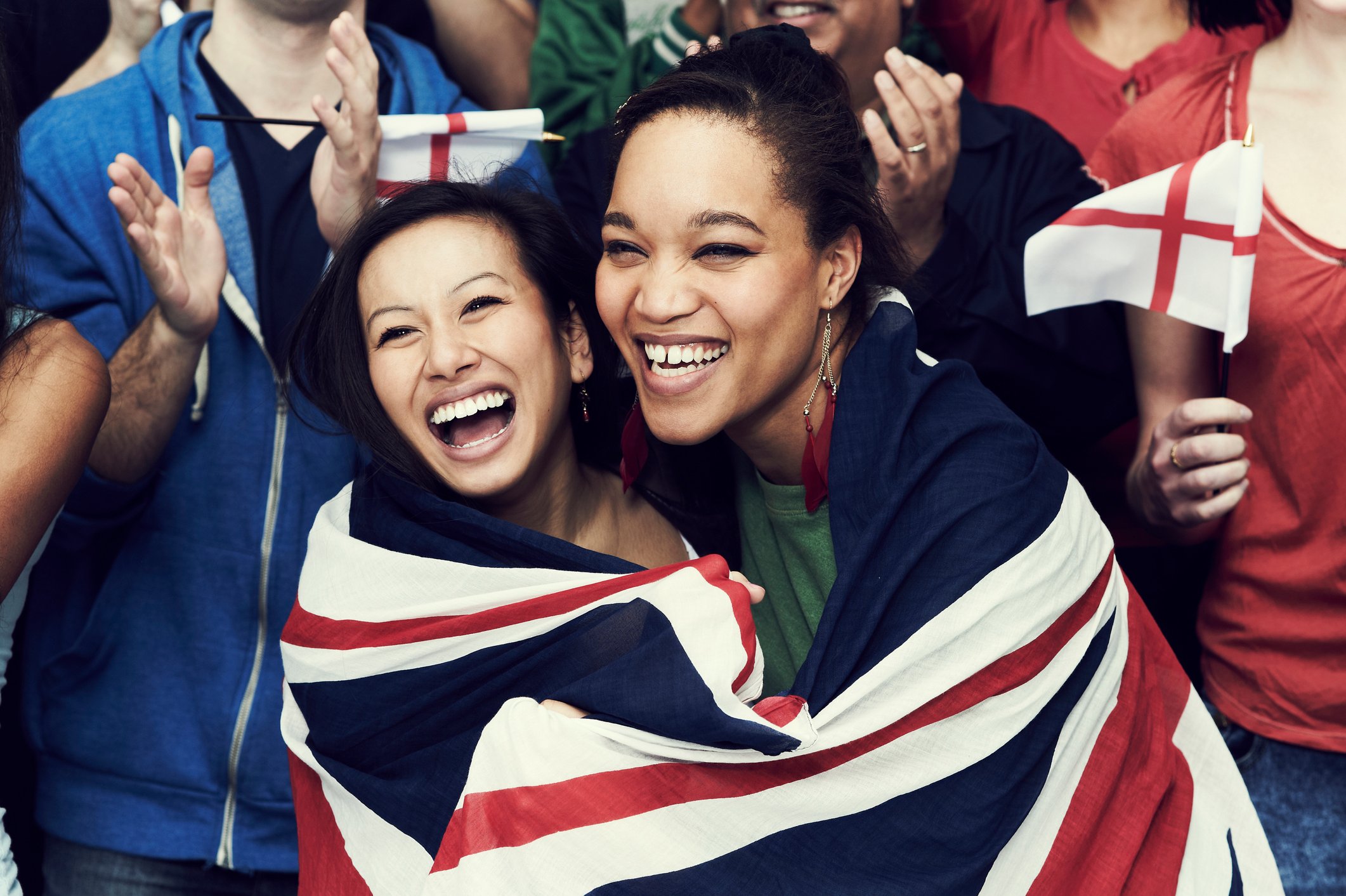 Two women smiling, both wrapped in a United Kingdom flag.