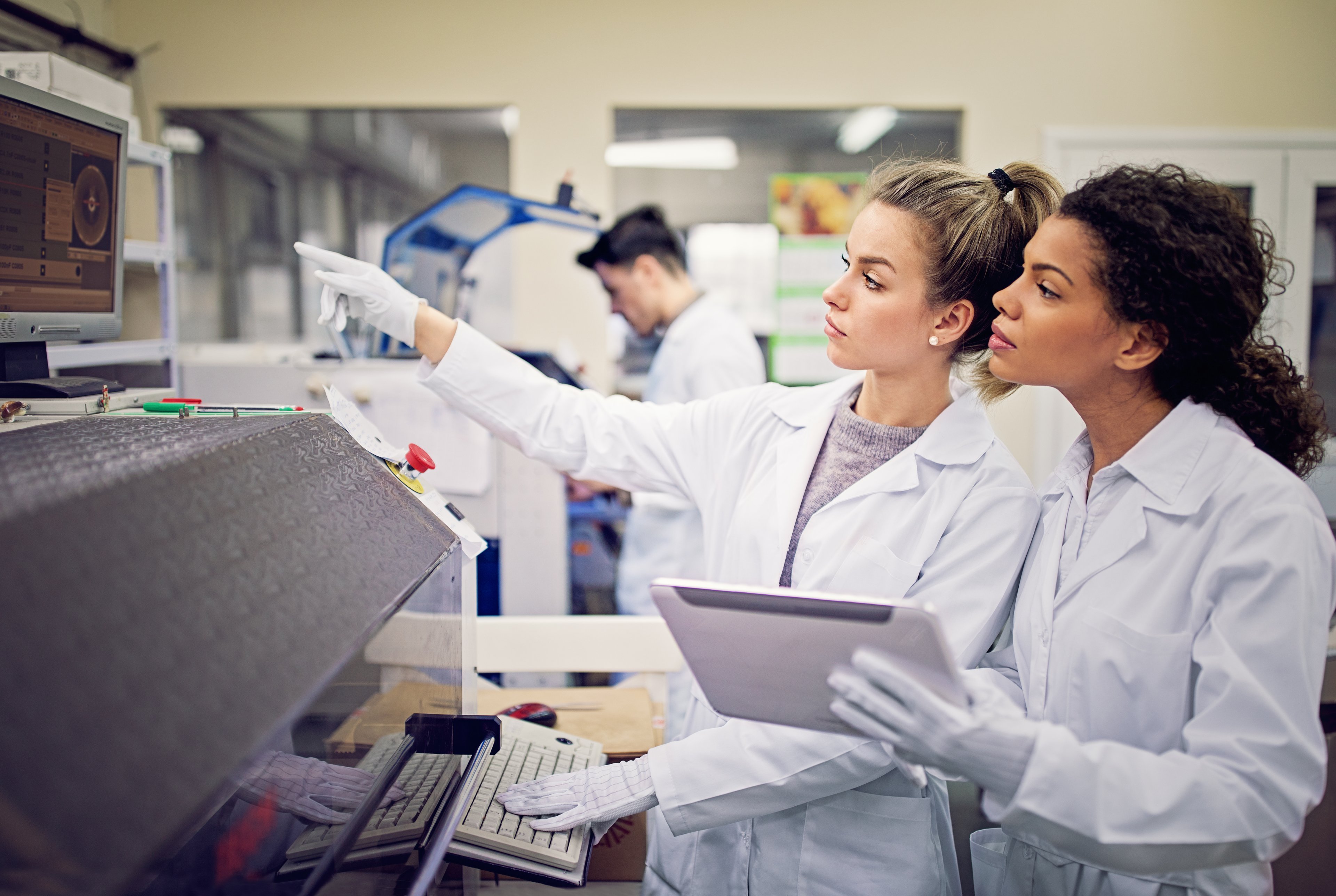 Engineers in a semiconductor testing facility work with a machine.