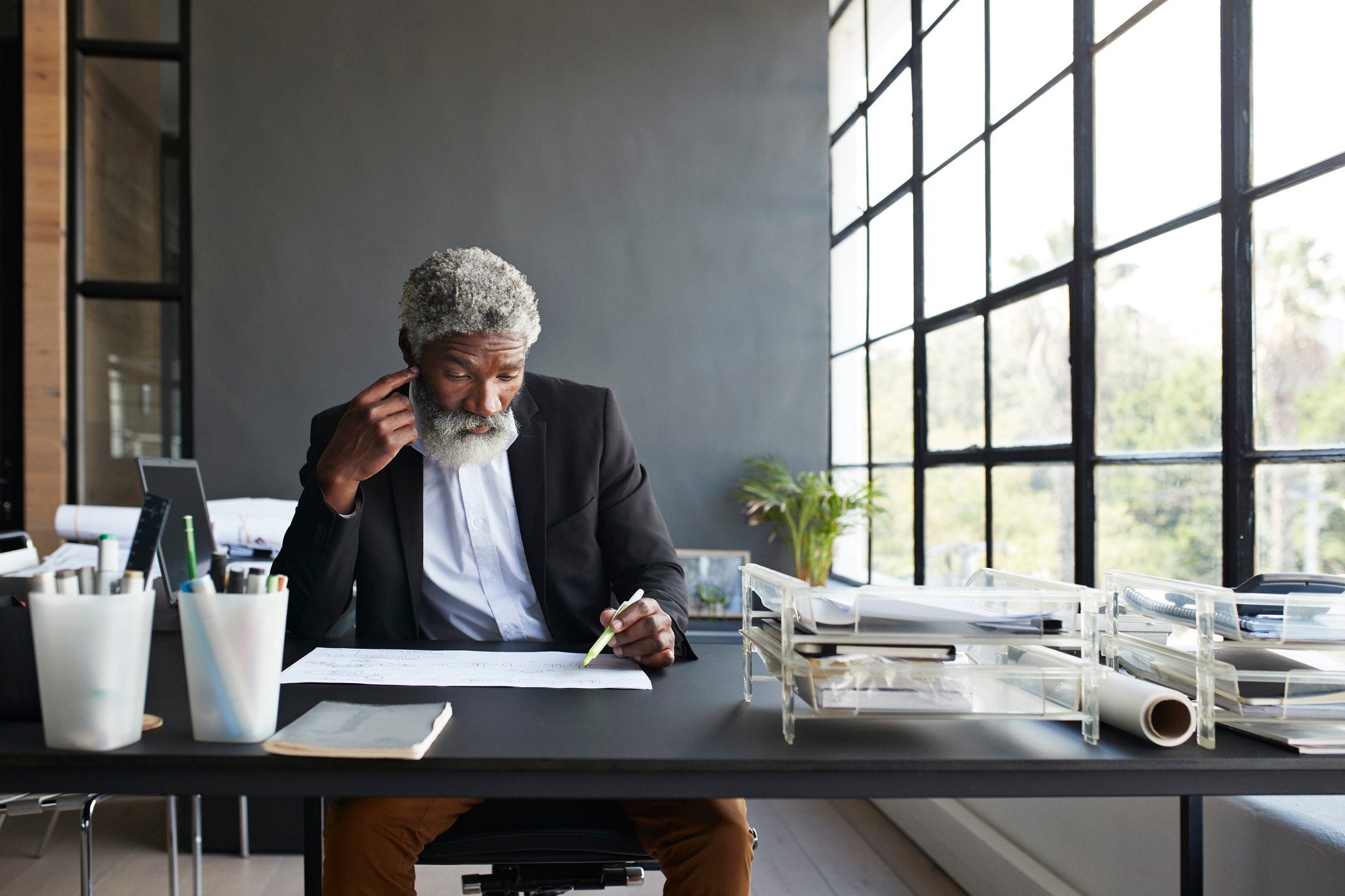 A person sitting at a desk and reading with a pen in their hand.