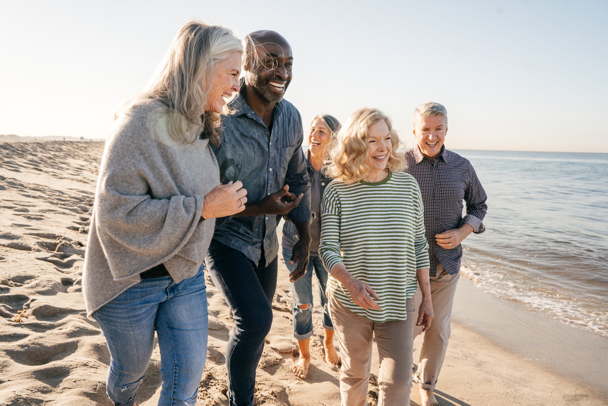 Five people on a beach smiling and laughing.