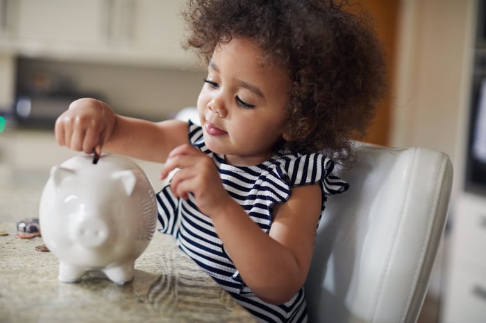 A child putting a coin in a piggy bank.