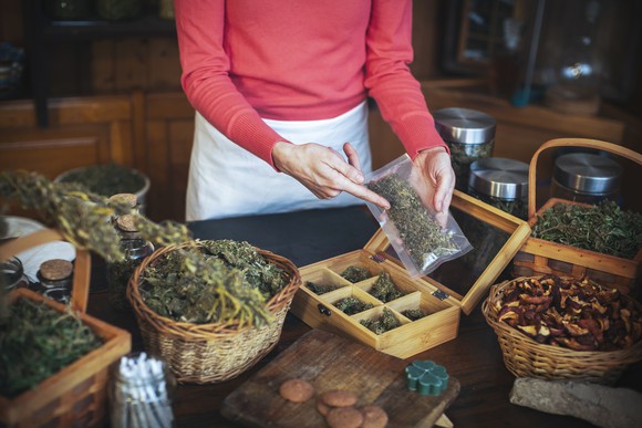 woman points to bags of cannabis in baskets on a table. 