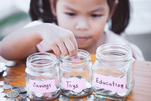 Child adding money to glass jars. 