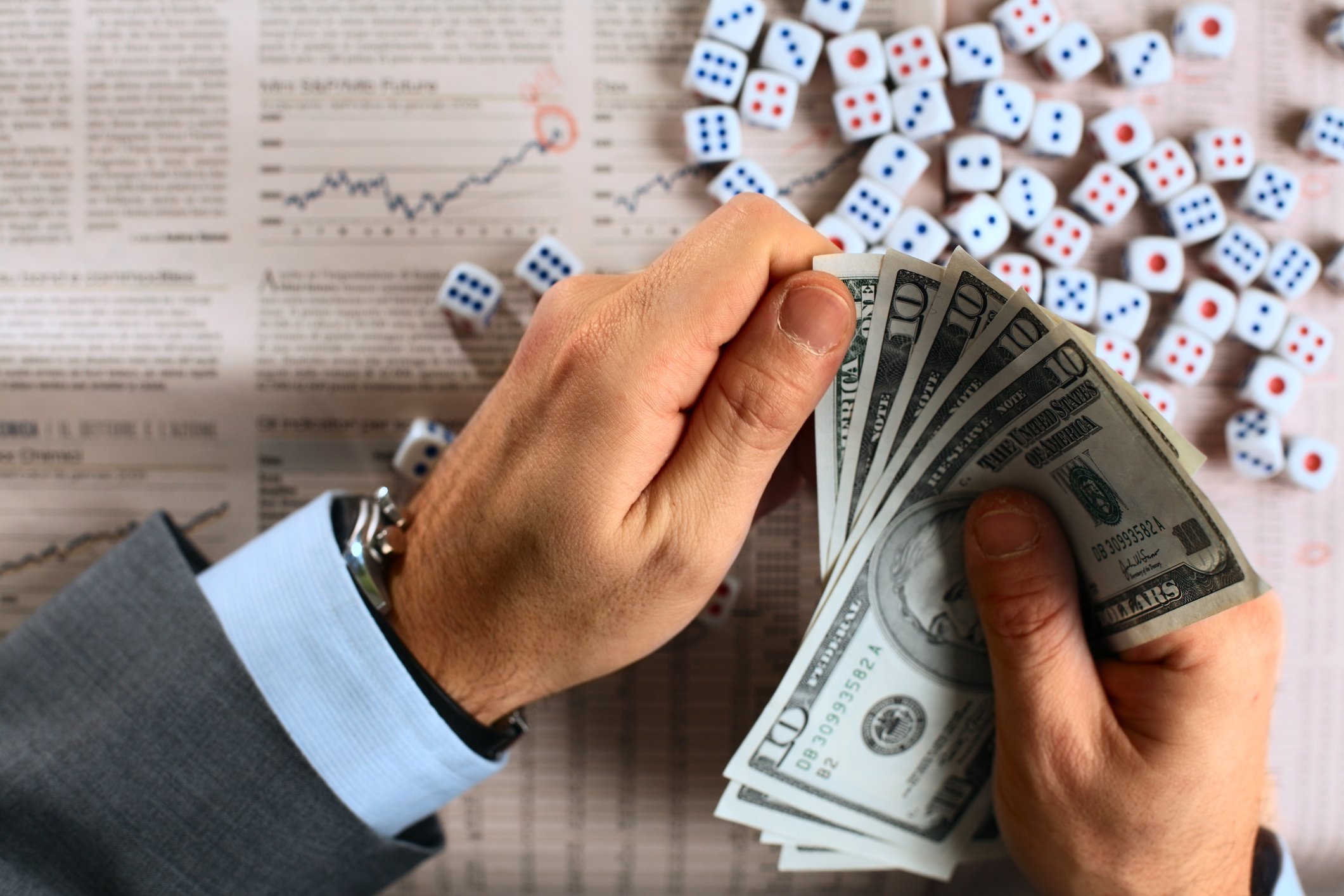 A man holding several $10 bills on a table with dice in it
