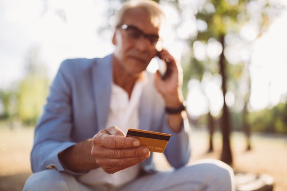 A person talking on the phone while holding a credit card.