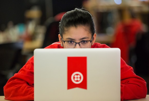 A person working on a laptop with a sticker of the Twilio logo