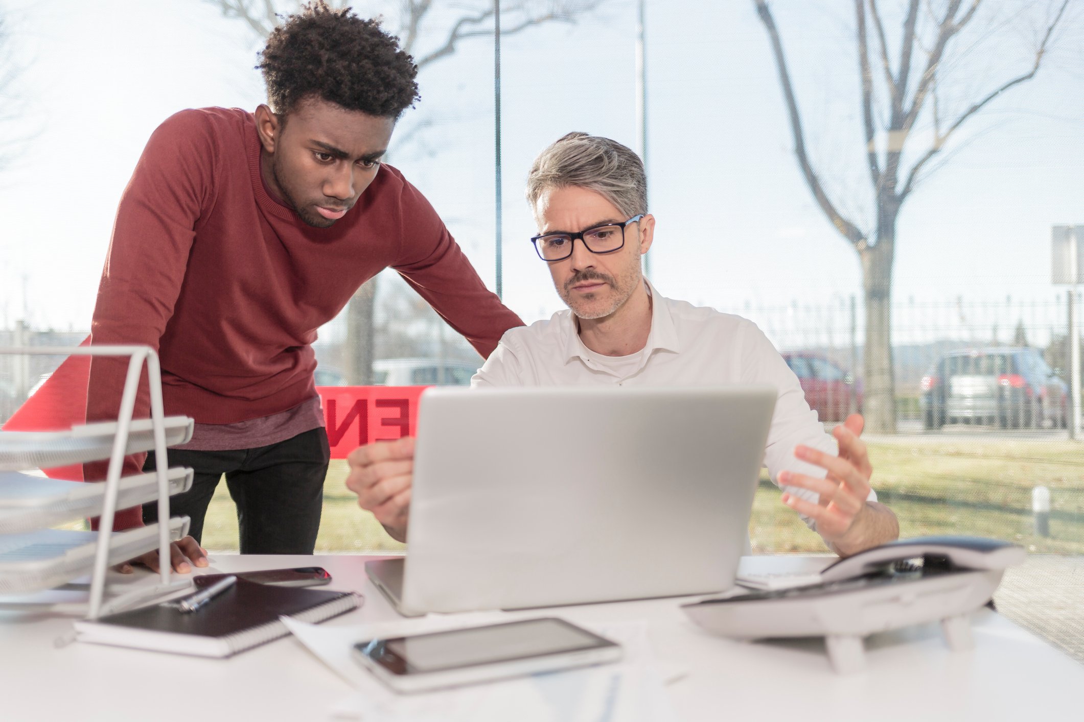 Two men look intently at stock data on a computer screen.