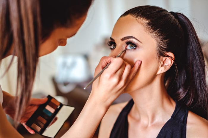 An esthetician applies eye makeup to a client.