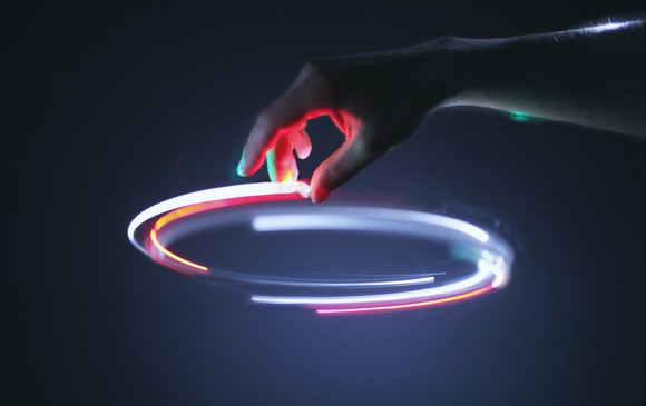 A hand tracing a streak of white light in a circle.