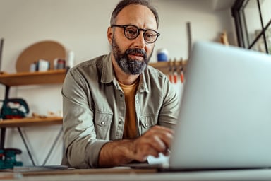 man using laptop in his home workshop.