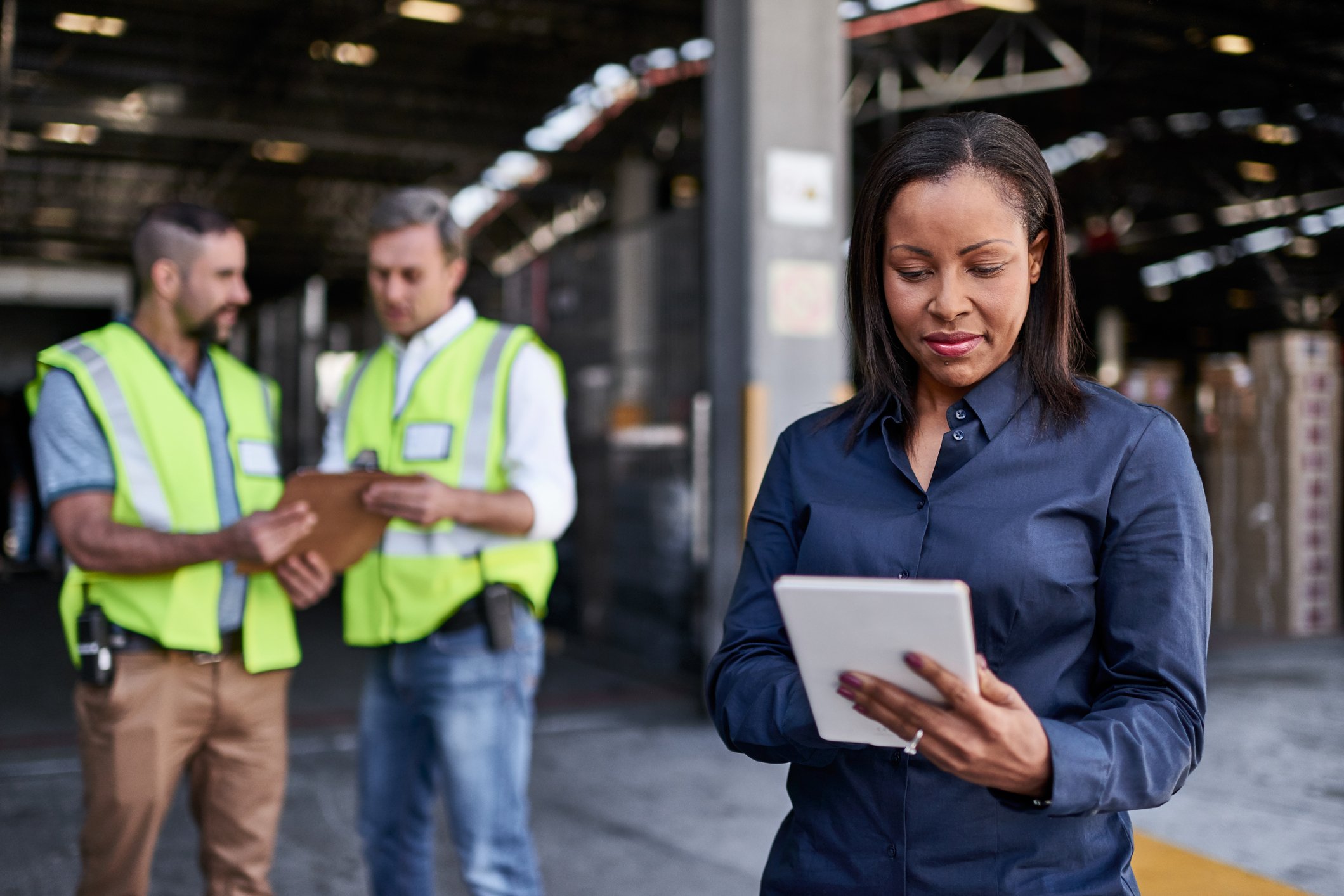 A manager using a tablet at a large manufacturing facility.