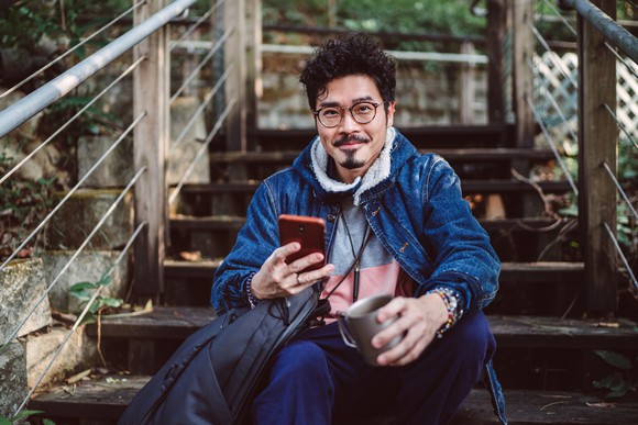 Smiling person sitting on stairs, holding phone.