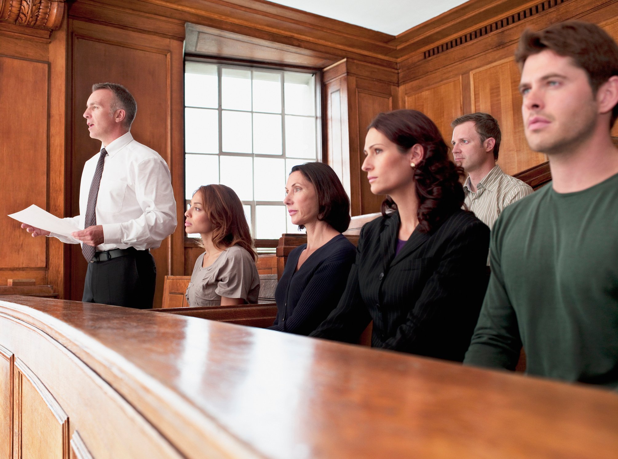 People sitting in a courtroom and one man standing and speaking.