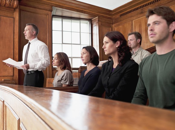 People sitting in a courtroom and one man standing and speaking.