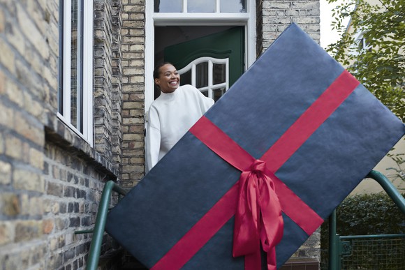 Person on doorstep behind a huge wrapped gift box.