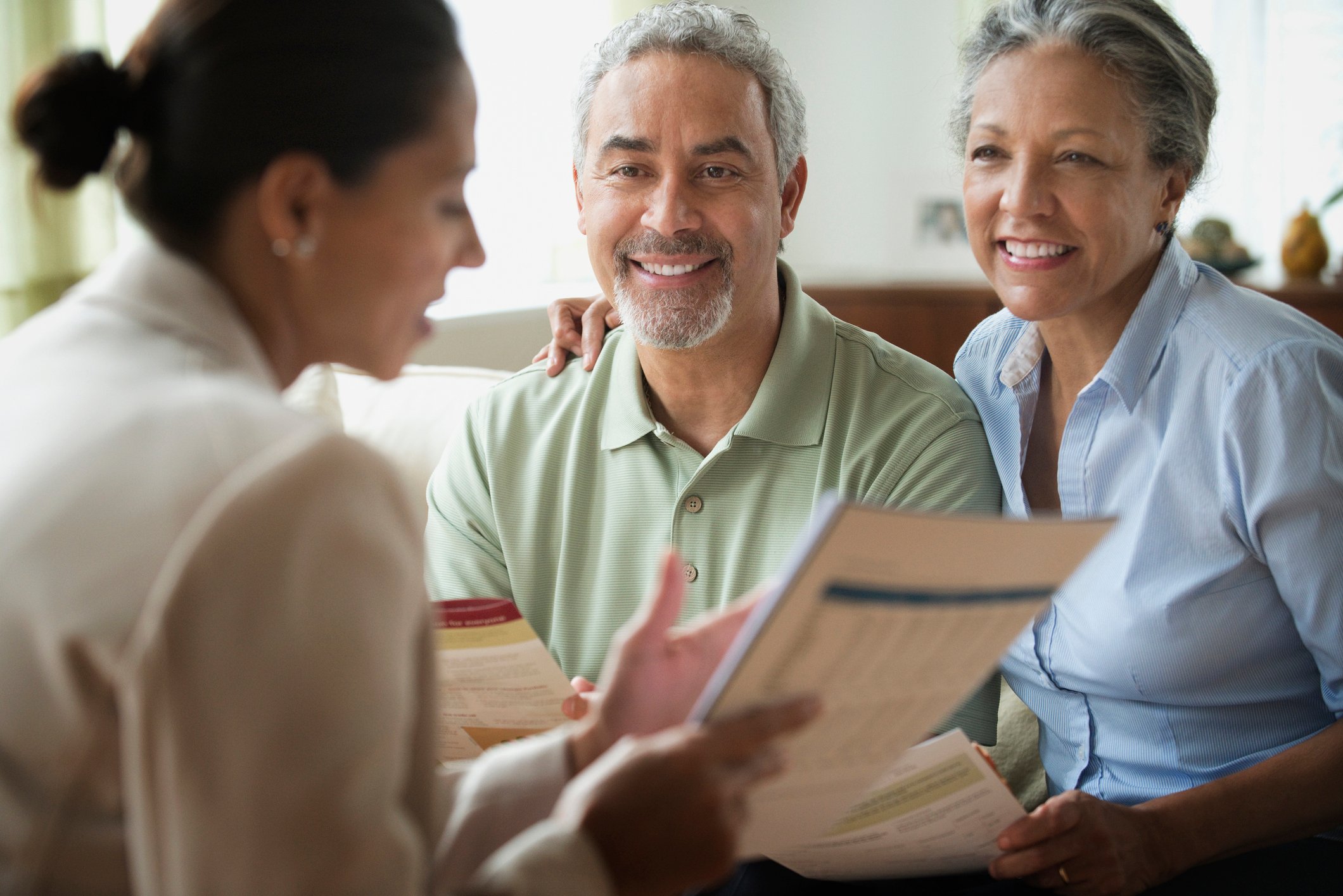 A middle-aged couple reviewing documents with an insurance broker.