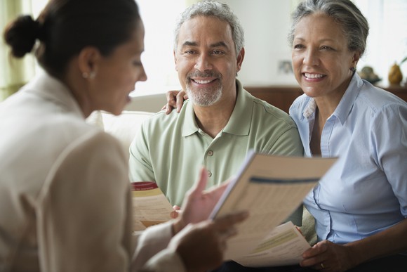 A middle-aged couple reviewing documents with an insurance broker.