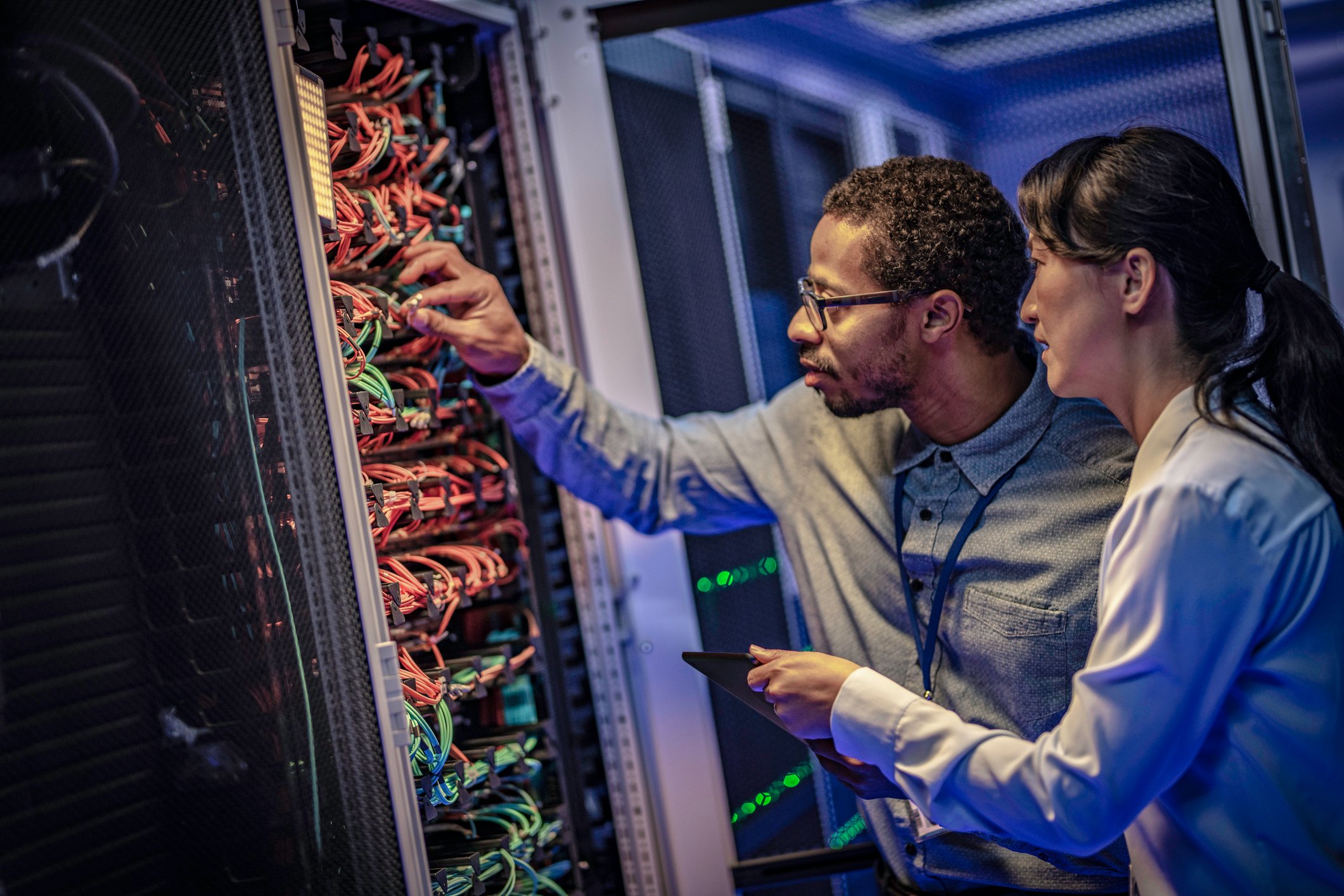 A man and a woman adjusting a computer server.