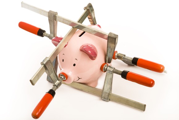 a piggy bank has stress clamps pushing in on it from different directions