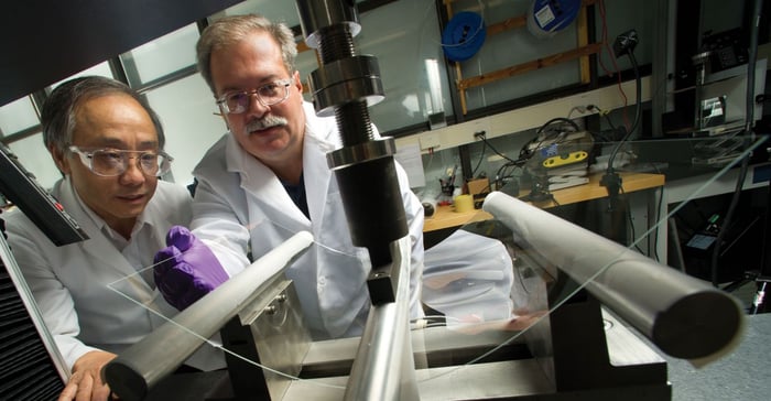 Two Corning researchers test a sheet of glass.