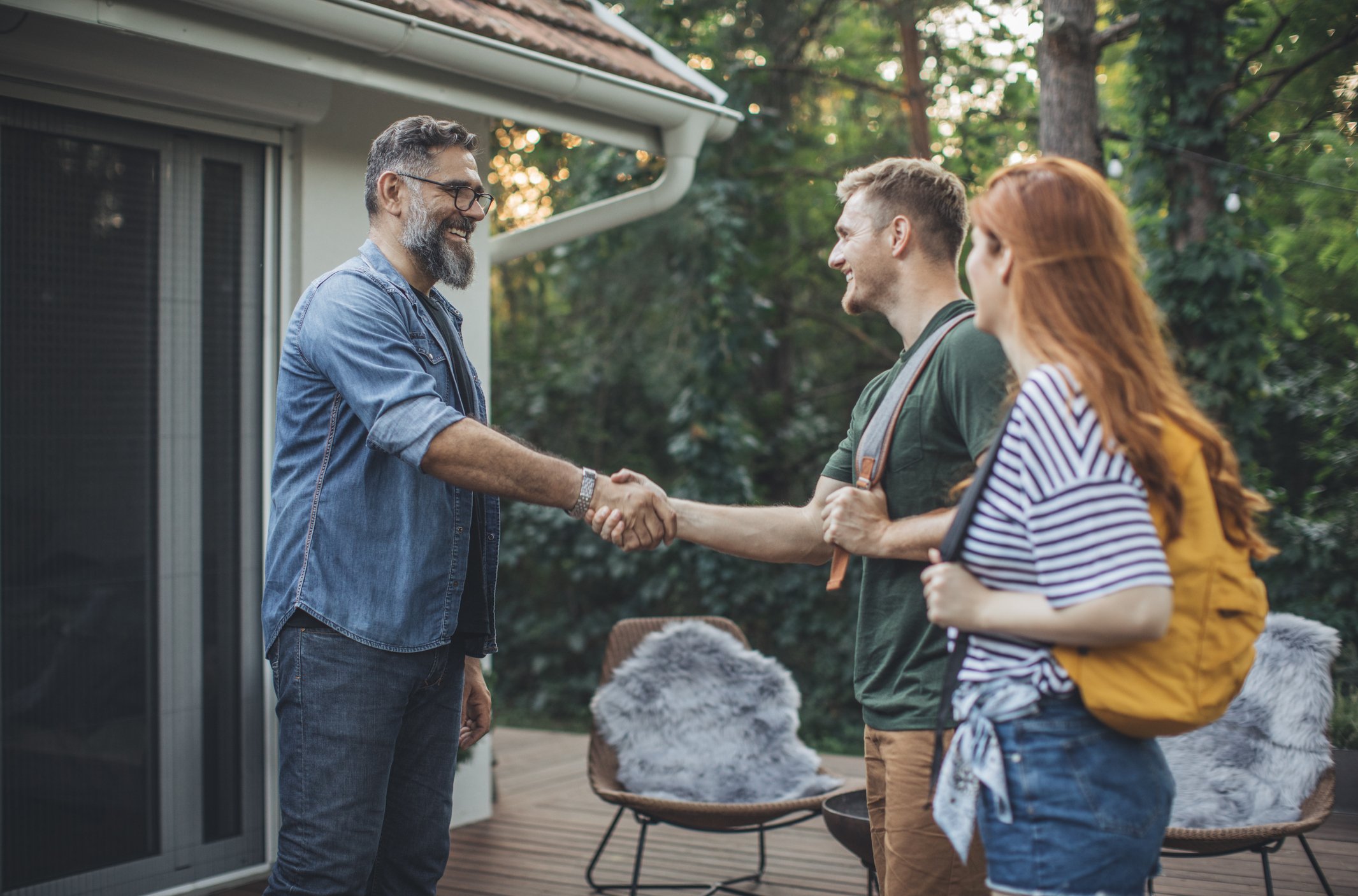 People with backpacks meeting someone on house patio.