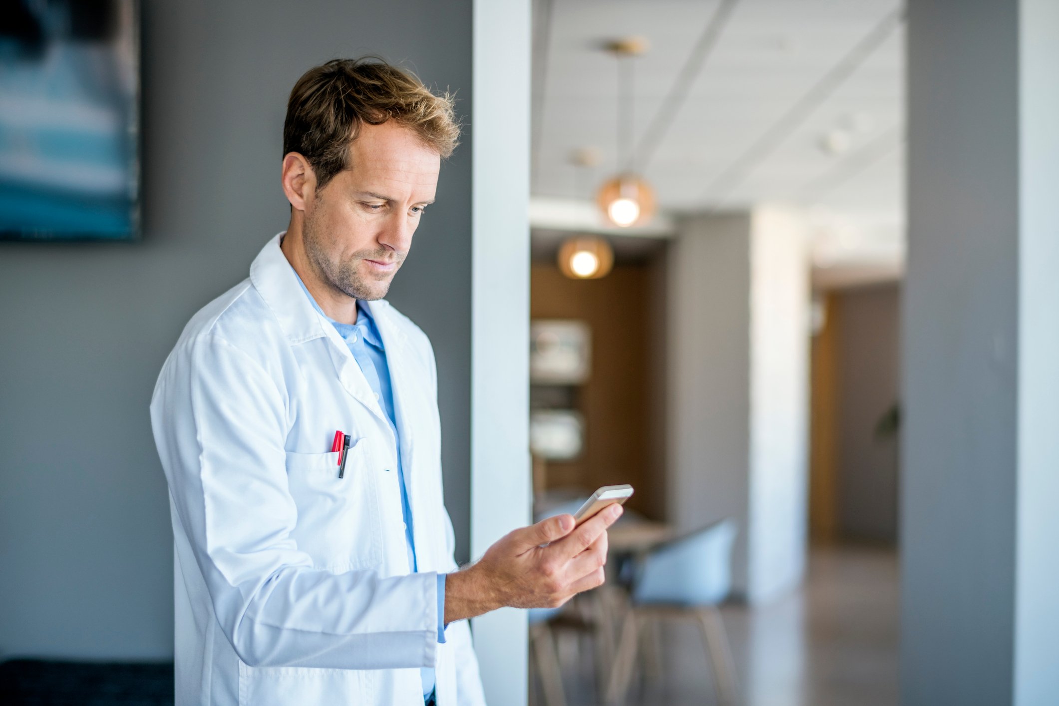A doctor looking at a cell phone.