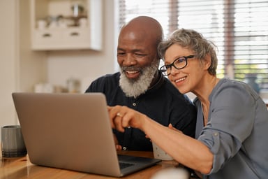 Older couple smiling with laptop
