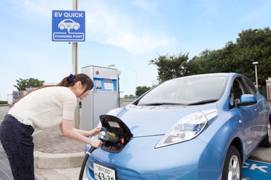 A young woman charging an electric car.