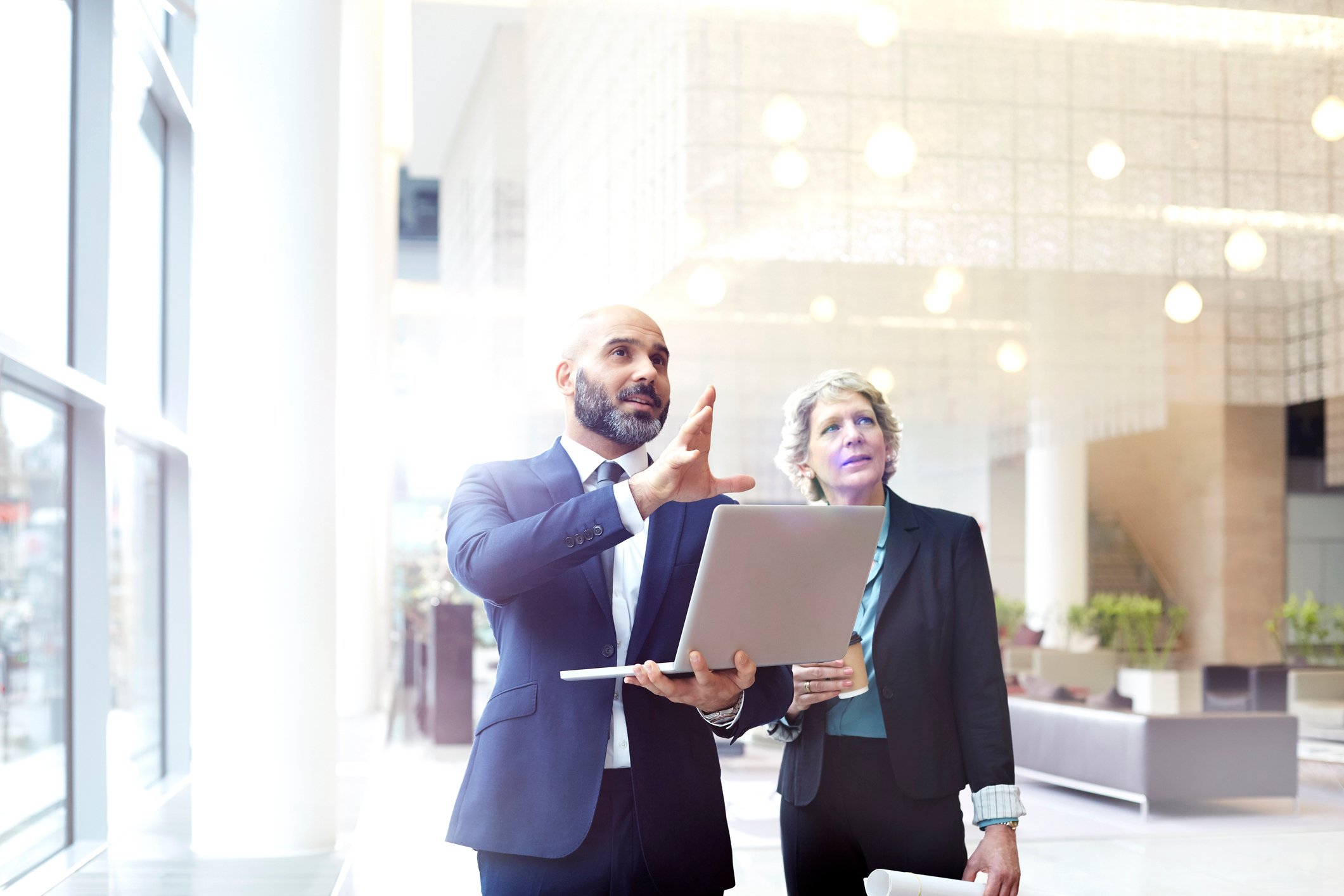 Businessperson with laptop explaining something to another.