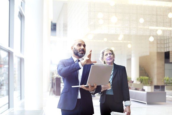 Businessperson with laptop explaining something to another.