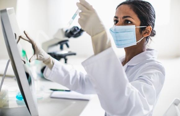 A researcher holding up a test tube and examining it.