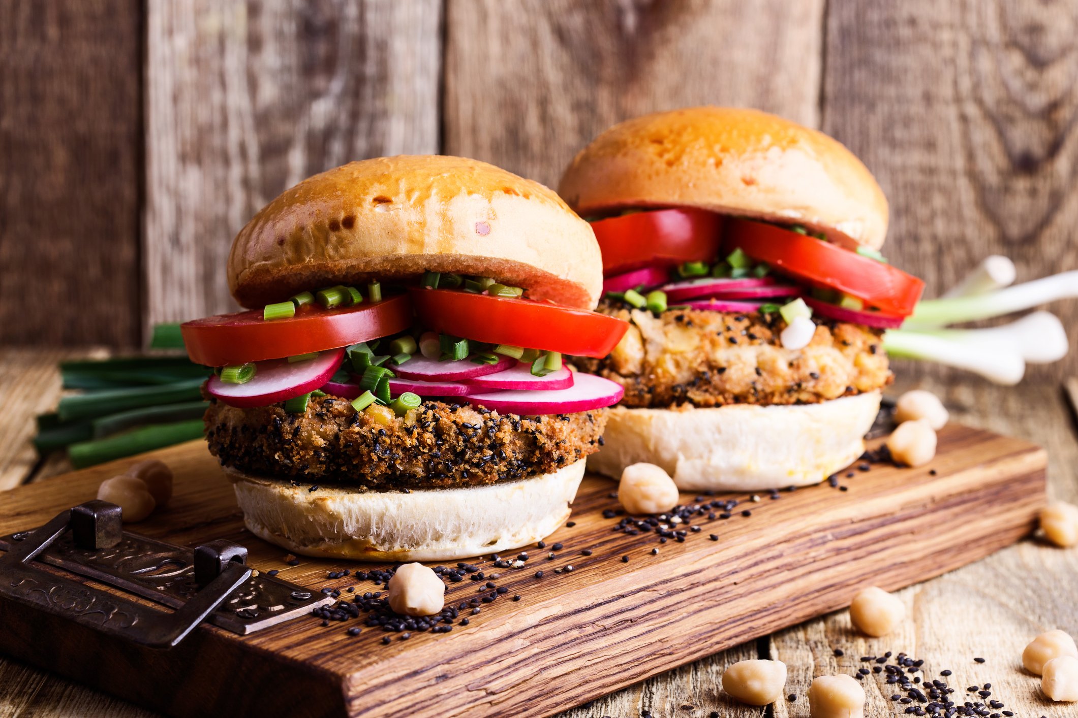 Two plant-based burgers on a wooden board.