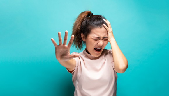 A grimacing woman gestures as if to say stop.