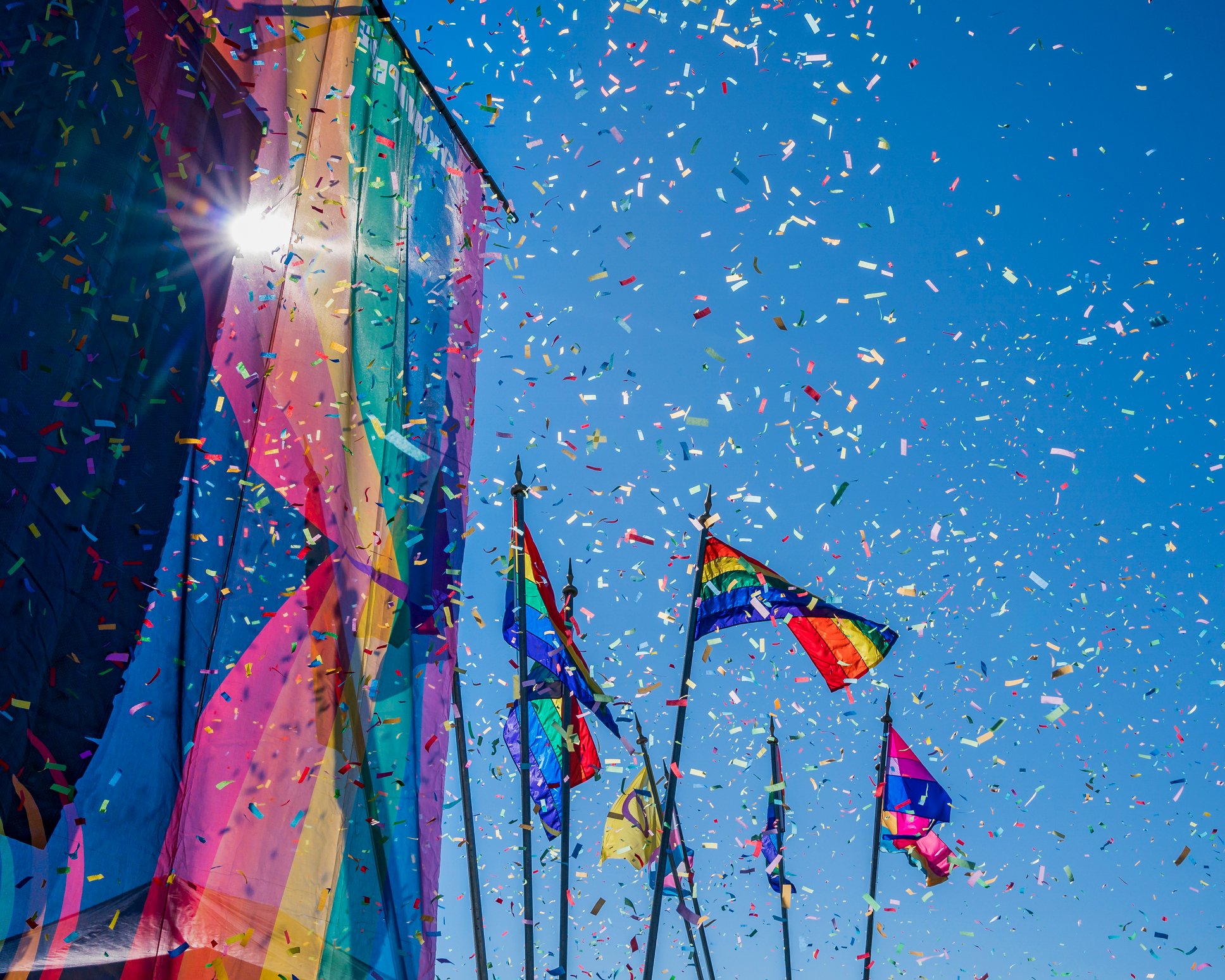 Rainbow flags on display amid confetti shower.