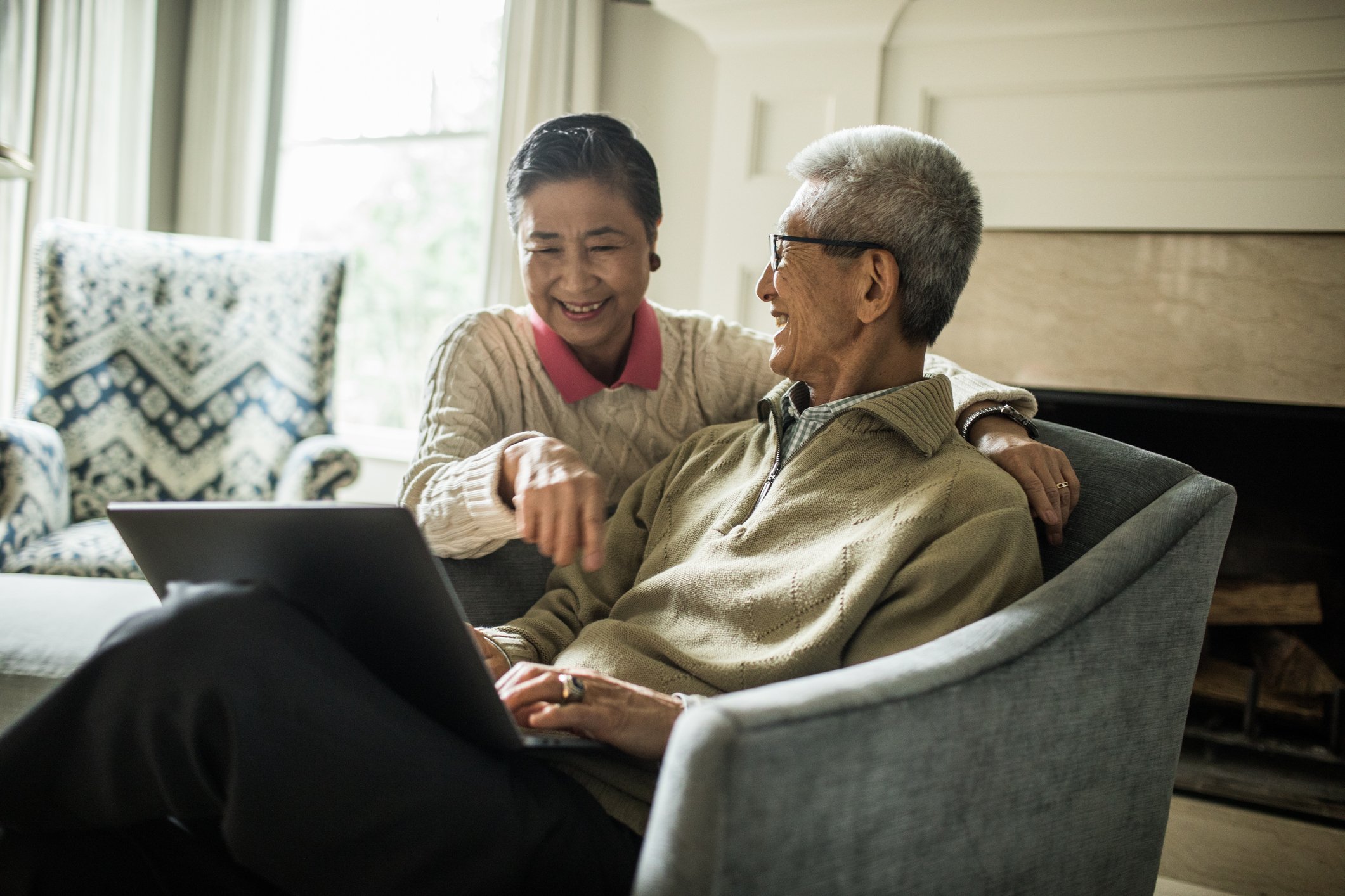 Smiling seniors talking and looking at laptop