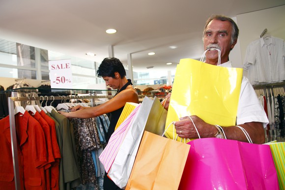 A couple shopping, with a man carry an overwhelming number of bags.