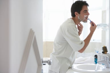 Man Shaving While Looking in Mirror